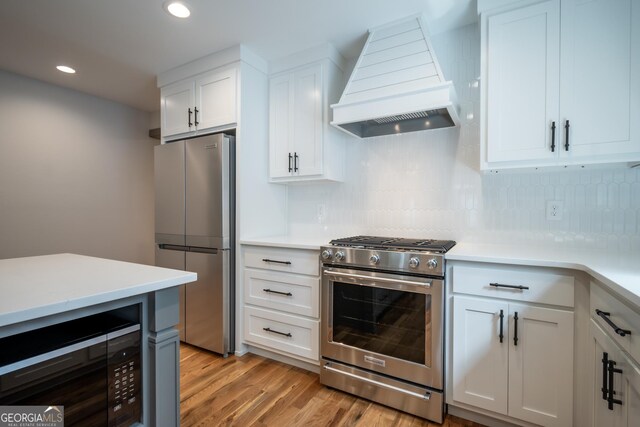215 Holman Ave, Athens, GA 30606 - kitchen featuring stainless steel appliances, premium range hood, light countertops, tasteful backsplash, and white cabinets