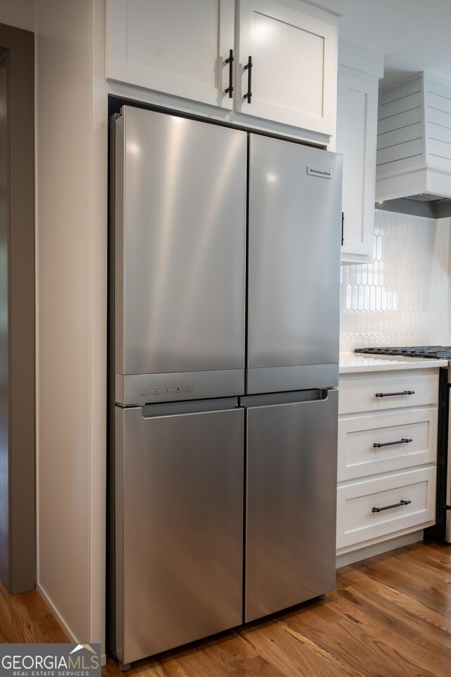215 Holman Ave, Athens, GA 30606 - kitchen with stainless steel refrigerator, premium range hood, white cabinetry, and decorative backsplash
