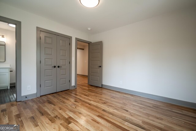 215 Holman Ave, Athens, GA 30606 - unfurnished bedroom with light wood-style floors, a closet, baseboards, and connected bathroom