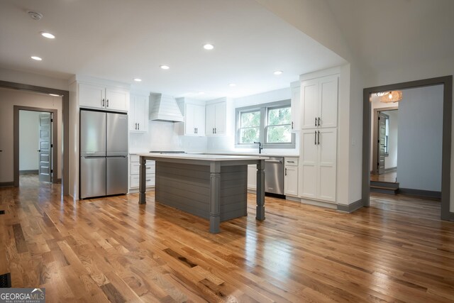 215 Holman Ave, Athens, GA 30606 - kitchen featuring appliances with stainless steel finishes, custom exhaust hood, white cabinets, light wood-style flooring, and recessed lighting