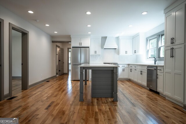 215 Holman Ave, Athens, GA 30606 - kitchen with appliances with stainless steel finishes, premium range hood, a breakfast bar area, wood finished floors, and a center island