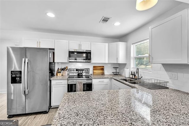 2912 Palm Dr, East Point, GA 30344 - kitchen featuring appliances with stainless steel finishes, a sink, white cabinets, light stone countertops, and tasteful backsplash
