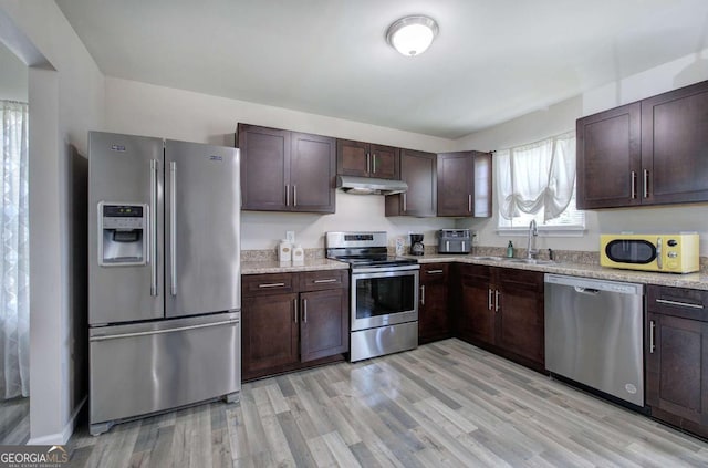 230 Louise Ln, Calhoun, GA 30701 - kitchen with stainless steel appliances, dark brown cabinetry, light wood-style floors, under cabinet range hood, and light stone countertops