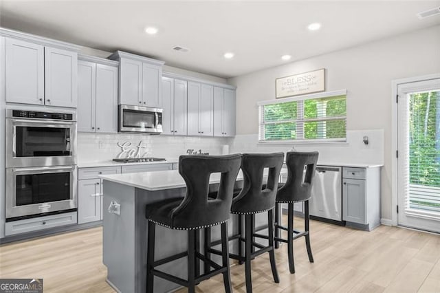 361 Traditions Ln, Hampton, GA 30228 - kitchen featuring stainless steel appliances, light countertops, a center island, a breakfast bar area, and tasteful backsplash