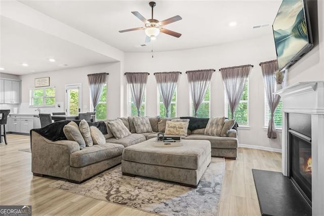 361 Traditions Ln, Hampton, GA 30228 - living area with a fireplace with flush hearth, a ceiling fan, light wood-style floors, recessed lighting, and baseboards