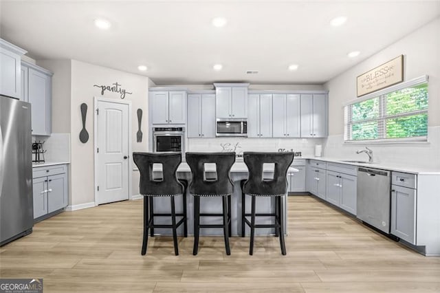 361 Traditions Ln, Hampton, GA 30228 - kitchen featuring stainless steel appliances, gray cabinetry, a kitchen breakfast bar, decorative backsplash, and a kitchen island
