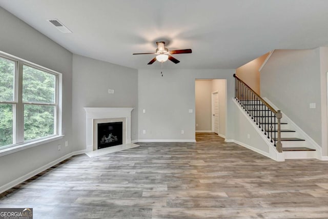 7760 Hansel Ln, Lithonia, GA 30058 - unfurnished living room with a ceiling fan, stairway, wood finished floors, a fireplace with raised hearth, and baseboards