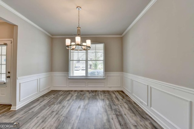 7760 Hansel Ln, Lithonia, GA 30058 - unfurnished dining area with a chandelier, wood finished floors, wainscoting, ornamental molding, and a decorative wall