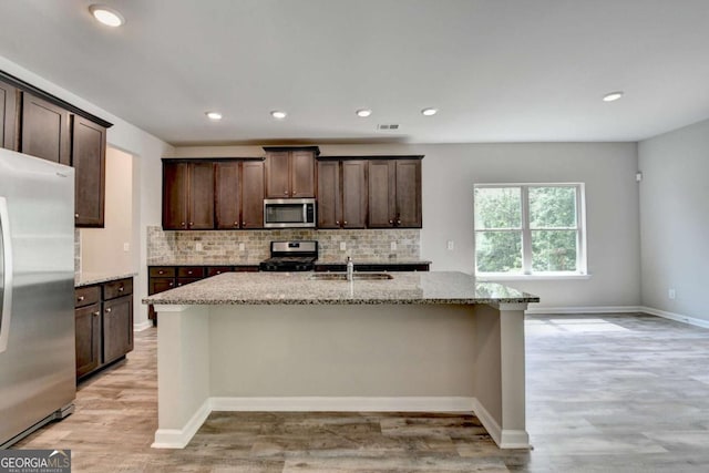 7760 Hansel Ln, Lithonia, GA 30058 - kitchen with appliances with stainless steel finishes, a sink, tasteful backsplash, light stone counters, and dark brown cabinets
