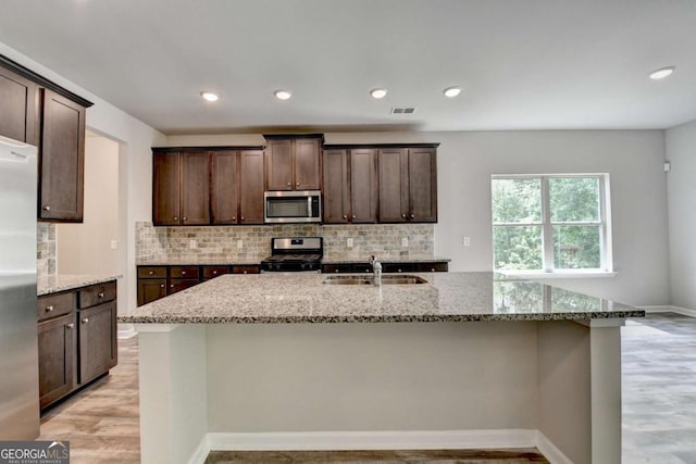 7760 Hansel Ln, Lithonia, GA 30058 - kitchen featuring stainless steel appliances, a sink, light stone countertops, light wood-style flooring, and backsplash