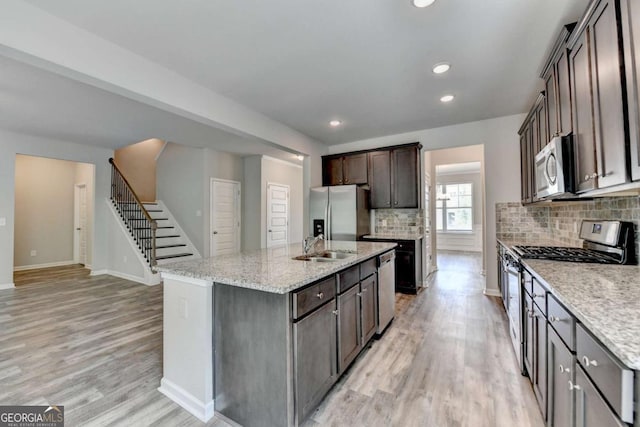 7760 Hansel Ln, Lithonia, GA 30058 - kitchen with appliances with stainless steel finishes, backsplash, light wood-type flooring, a center island with sink, and baseboards