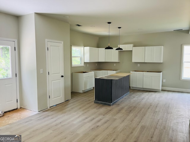 8035 Buffet Trl, Riverdale, GA 30296 - kitchen with a center island, light wood-style floors, white cabinetry, and healthy amount of natural light