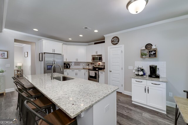 433 Wilson Dr, Mcdonough, GA 30252 - kitchen featuring appliances with stainless steel finishes, crown molding, tasteful backsplash, dark wood finished floors, and a kitchen bar