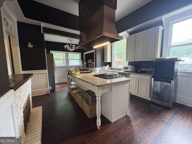 435 Jackson St, Locust Grove, GA 30248 - kitchen with dark wood-style flooring, a chandelier, island range hood, stainless steel appliances, and wainscoting