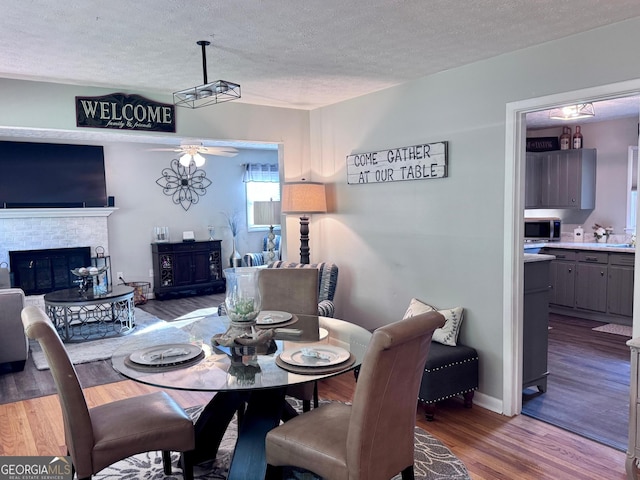 107 Woodhaven Dr, Stockbridge, GA 30281 - dining space featuring wood finished floors, a textured ceiling, a ceiling fan, and a glass covered fireplace