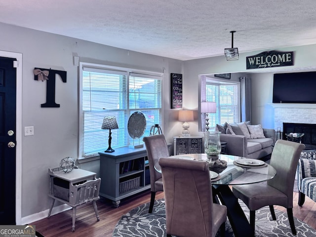 107 Woodhaven Dr, Stockbridge, GA 30281 - dining space featuring wood finished floors, healthy amount of natural light, a textured ceiling, and a brick fireplace