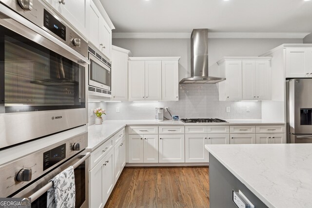 3998 Commodore Dr, Atlanta, GA 30341 - kitchen with wall chimney range hood, appliances with stainless steel finishes, wood finished floors, and white cabinetry