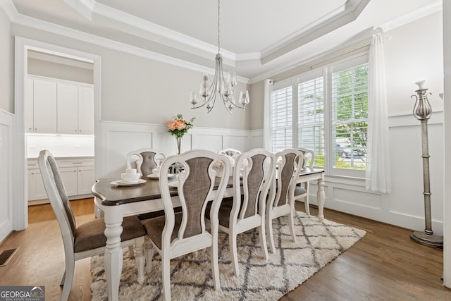 3998 Commodore Dr, Atlanta, GA 30341 - dining area featuring a decorative wall, a raised ceiling, a chandelier, wainscoting, and light wood-type flooring