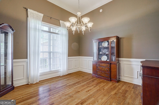 1621 White Oak Cv, Loganville, GA 30052 - unfurnished dining area featuring a chandelier, light wood-style flooring, ornamental molding, a wainscoted wall, and a decorative wall