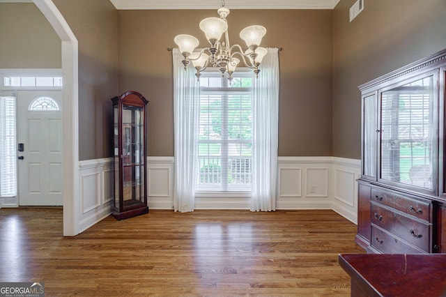 1621 White Oak Cv, Loganville, GA 30052 - foyer with arched walkways, a chandelier, wood finished floors, wainscoting, and a decorative wall