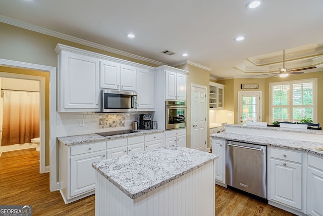 1621 White Oak Cv, Loganville, GA 30052 - kitchen featuring appliances with stainless steel finishes, ornamental molding, wood finished floors, white cabinetry, and recessed lighting