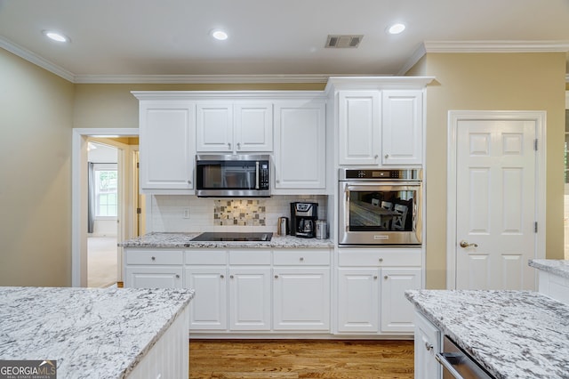 1621 White Oak Cv, Loganville, GA 30052 - kitchen with appliances with stainless steel finishes, ornamental molding, light wood finished floors, backsplash, and white cabinets