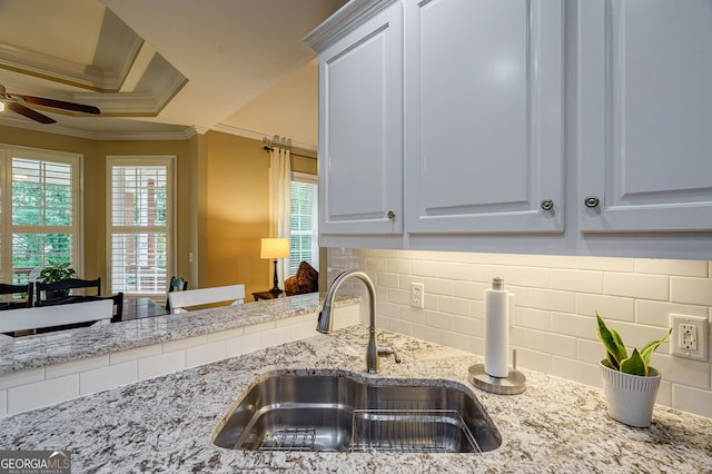 1621 White Oak Cv, Loganville, GA 30052 - kitchen with a sink, crown molding, a ceiling fan, tasteful backsplash, and light stone counters