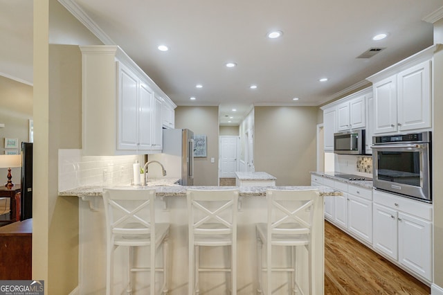 1621 White Oak Cv, Loganville, GA 30052 - kitchen with appliances with stainless steel finishes, crown molding, recessed lighting, backsplash, and a peninsula