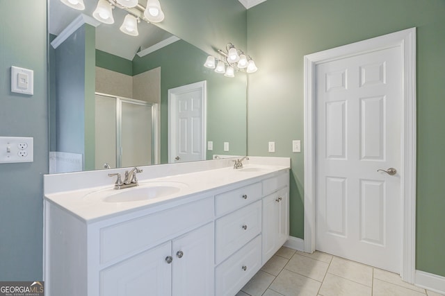 1621 White Oak Cv, Loganville, GA 30052 - full bathroom featuring tile patterned floors, a shower stall, double vanity, vaulted ceiling, and baseboards