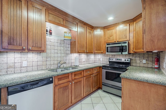 1621 White Oak Cv, Loganville, GA 30052 - kitchen featuring appliances with stainless steel finishes, a sink, tasteful backsplash, light tile patterned floors, and brown cabinetry