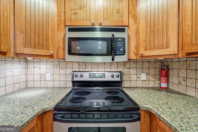 1621 White Oak Cv, Loganville, GA 30052 - kitchen with stainless steel appliances, decorative backsplash, and brown cabinets