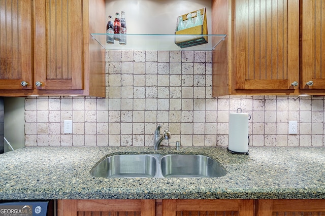 1621 White Oak Cv, Loganville, GA 30052 - kitchen featuring a sink, brown cabinetry, backsplash, and dark stone countertops