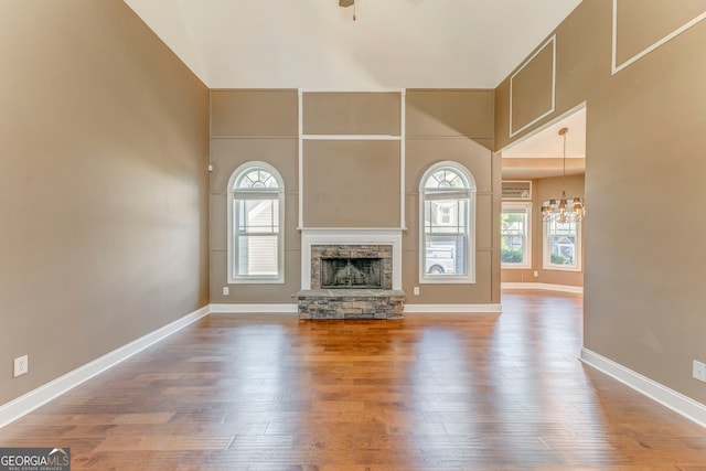 100 Harmony Ct, Dallas, GA 30157 - unfurnished living room with healthy amount of natural light, a chandelier, a high ceiling, a stone fireplace, and wood finished floors