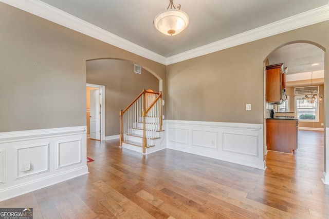 100 Harmony Ct, Dallas, GA 30157 - empty room featuring arched walkways, crown molding, light wood-style flooring, stairway, and wainscoting