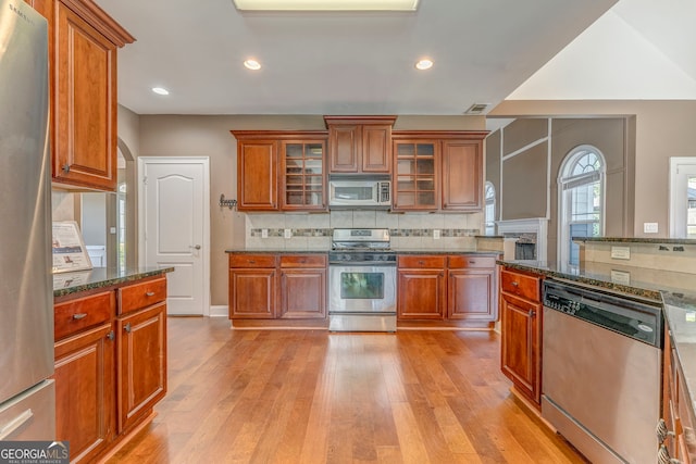 100 Harmony Ct, Dallas, GA 30157 - kitchen featuring stainless steel appliances, light wood finished floors, decorative backsplash, brown cabinets, and glass insert cabinets