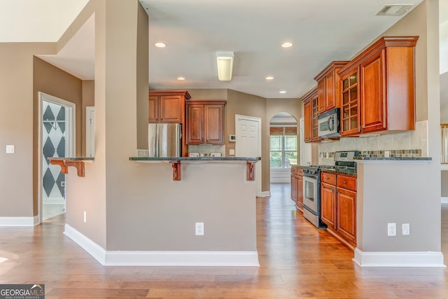 100 Harmony Ct, Dallas, GA 30157 - kitchen featuring appliances with stainless steel finishes, a kitchen bar, brown cabinets, light wood-type flooring, and recessed lighting