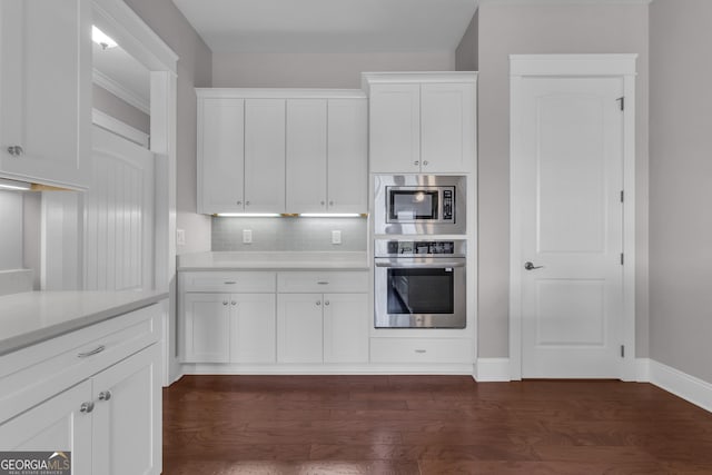 406 Vanderbilt Pkwy, Newnan, GA 30265 - kitchen featuring appliances with stainless steel finishes, white cabinetry, tasteful backsplash, and dark wood-style floors