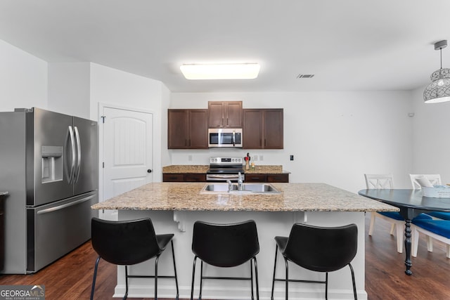 3993 Makeover Ct, South Fulton, GA 30349 - kitchen with appliances with stainless steel finishes, a sink, dark wood finished floors, a breakfast bar area, and dark brown cabinets