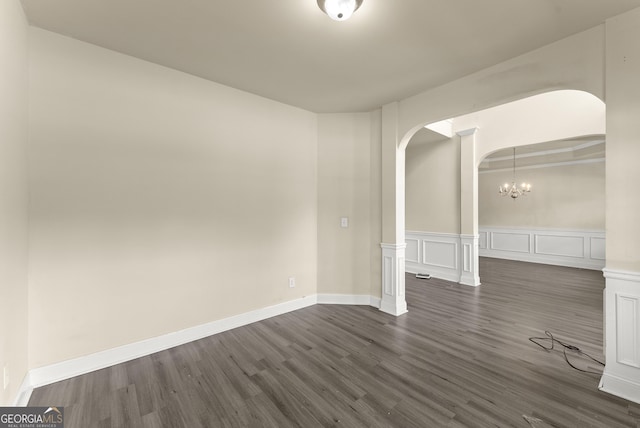 240 Somerset Dr, Dallas, GA 30132 - empty room with arched walkways, dark wood finished floors, a chandelier, a decorative wall, and wainscoting