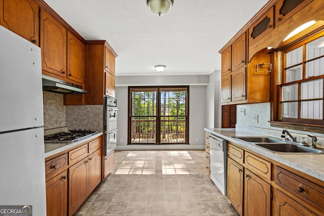 315 Burke Cir, Mcdonough, GA 30253 - kitchen featuring appliances with stainless steel finishes, a sink, under cabinet range hood, crown molding, and tasteful backsplash