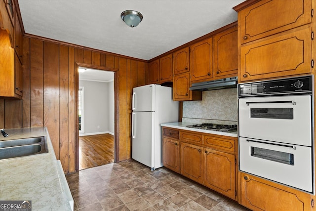 315 Burke Cir, Mcdonough, GA 30253 - kitchen with white appliances, under cabinet range hood, wood walls, light countertops, and backsplash