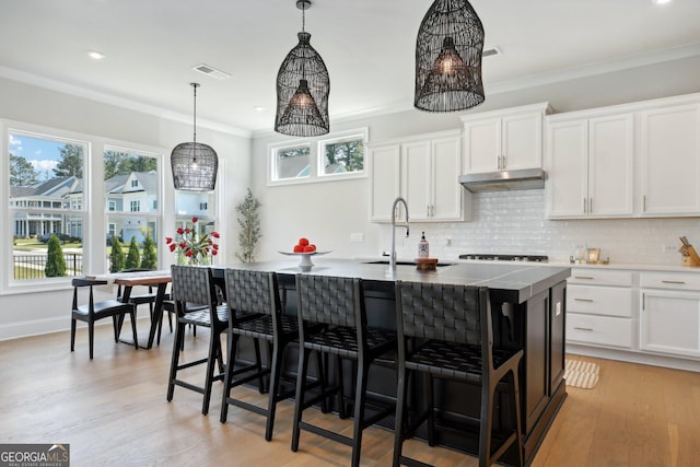 247 Widener Way, Peachtree City, GA 30269 - kitchen featuring under cabinet range hood, plenty of natural light, a kitchen bar, decorative backsplash, and crown molding