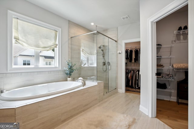 247 Widener Way, Peachtree City, GA 30269 - bathroom with a bath, a shower stall, a walk in closet, and wood finished floors