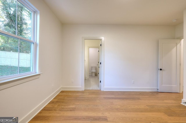 1947 Clark Dr, Tucker, GA 30084 - unfurnished bedroom featuring multiple windows, light wood-style floors, baseboards, and ensuite bathroom