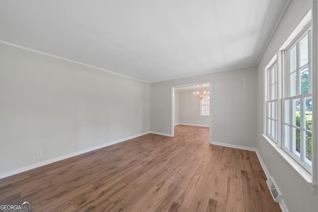 1173 Normandy Rd, Macon, GA 31210 - empty room with a chandelier, healthy amount of natural light, baseboards, wood finished floors, and crown molding