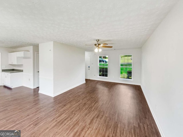 4311 Marci St, Snellville, GA 30039 - unfurnished living room featuring dark wood-style flooring, a textured ceiling, a ceiling fan, and baseboards