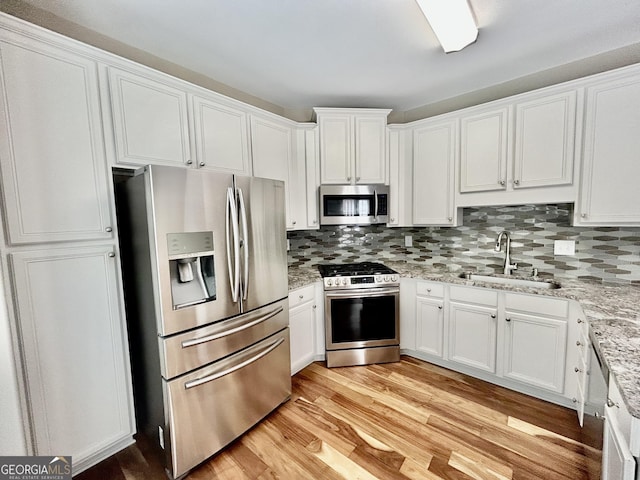 3988 Church View Ln, Suwanee, GA 30024 - kitchen with stainless steel appliances, white cabinetry, backsplash, and light wood-type flooring