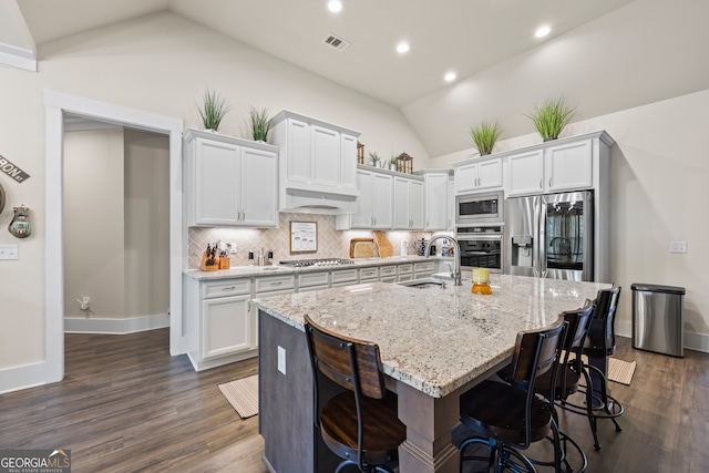 21 Little Creek Dr, Monroe, GA 30655 - kitchen featuring stainless steel appliances, lofted ceiling, decorative backsplash, a kitchen island with sink, and light stone countertops