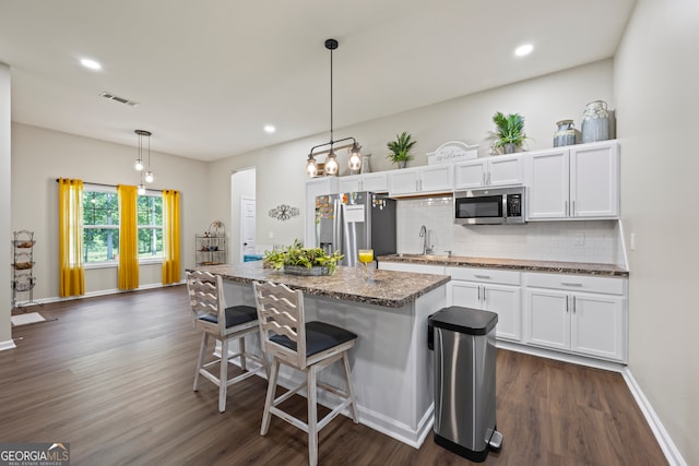 21 Little Creek Dr, Monroe, GA 30655 - kitchen with stainless steel appliances, dark wood-type flooring, white cabinetry, a breakfast bar, and tasteful backsplash