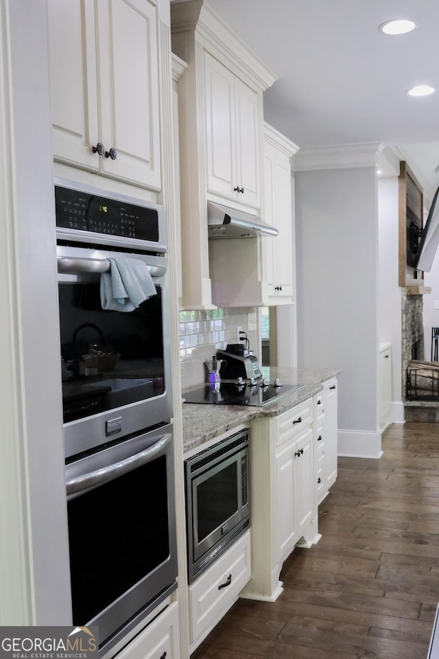 1761 Turtle Pond Dr, Watkinsville, GA 30677 - kitchen with appliances with stainless steel finishes, under cabinet range hood, crown molding, white cabinets, and decorative backsplash